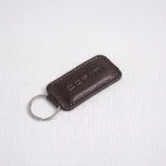 جاکلیدی چرمی قهوه‌ای تیره با لوگوی حک‌شده و لبه‌دوزی ظریف