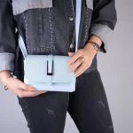 کیف کوچک دستی و دوشی دراتی رنگ آبی در دست مدل خانم